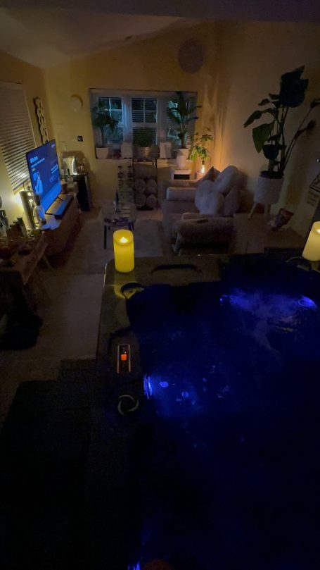 A warmly lit indoor space featuring a pool, TV, and comfortable seating.