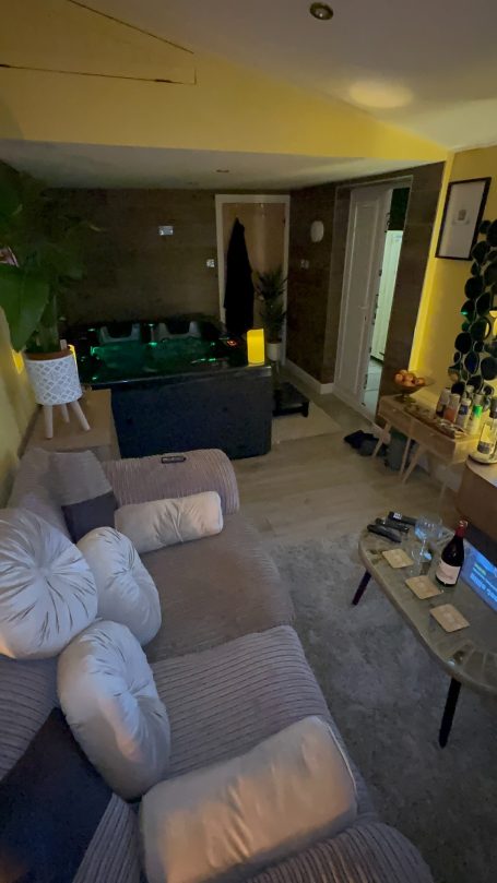 A cosy living room with a sofa, plants, low lighting, and decorative items on a coffee table.