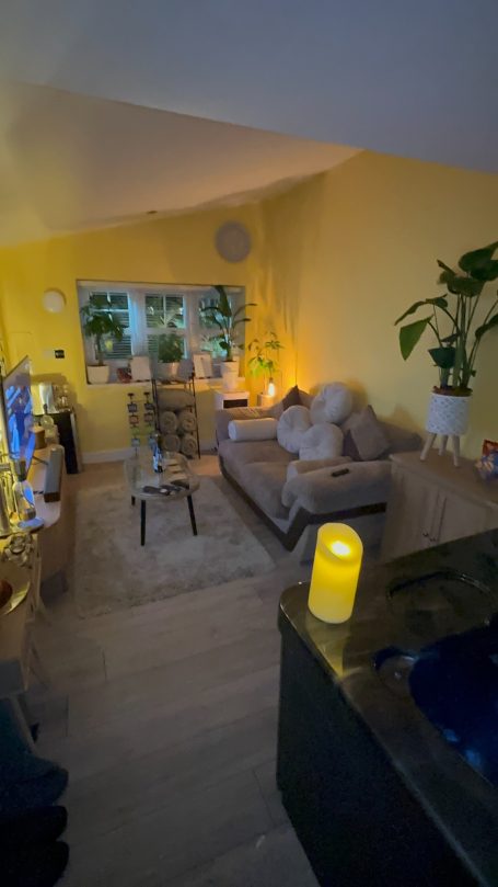 Cozy living room with yellow walls, plants, and soft lighting.