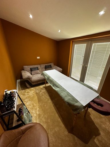 A small room with a brown wall, a sofa, and a long table beside a sliding door.