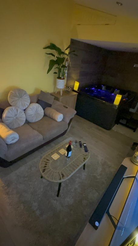 A modern living room with a beige sofa, coffee table, and a decorative fish tank.