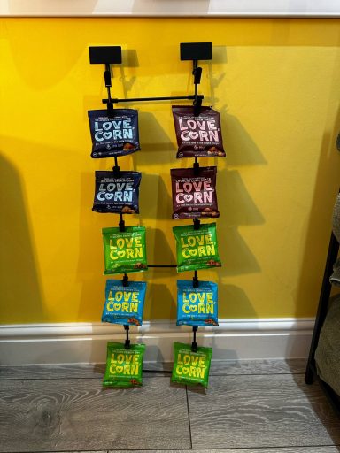 A rack displaying bags of crisps in various flavours against a yellow wall.