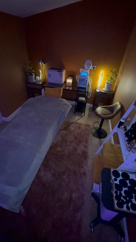 A dimly lit room featuring a massage bed and various treatment equipment.