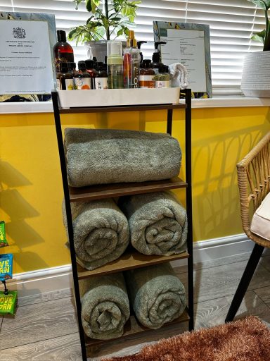 A shelf with neatly rolled green towels and informational signs in a bright room.