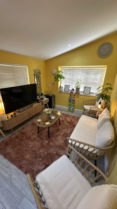 Lively yellow living room with two sofas, a coffee table, and a large TV.