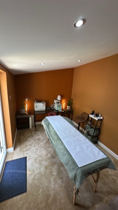 A calm spa room featuring a massage table and soothing amber walls.