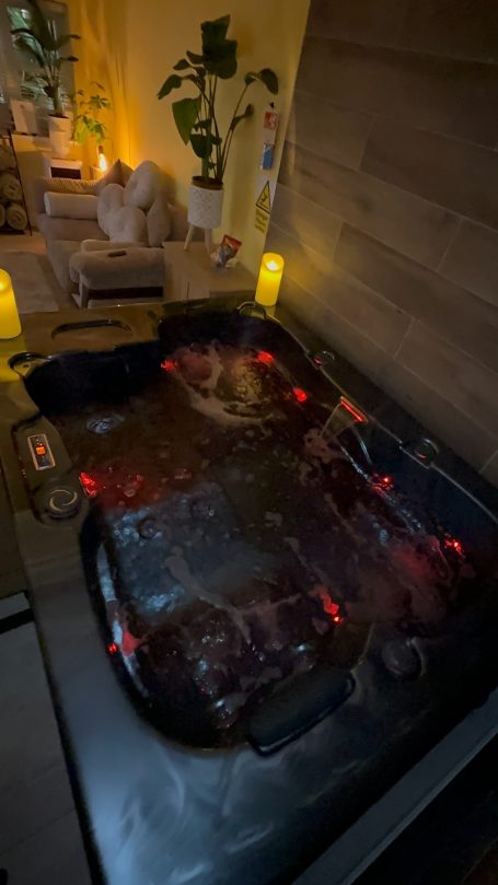 A dark hot tub with bubbling water and ambient lighting in a cozy indoor setting.