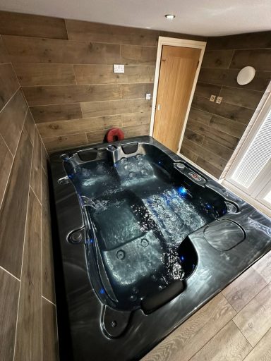 A modern hot tub in a wooden interior room, with ambient lighting.