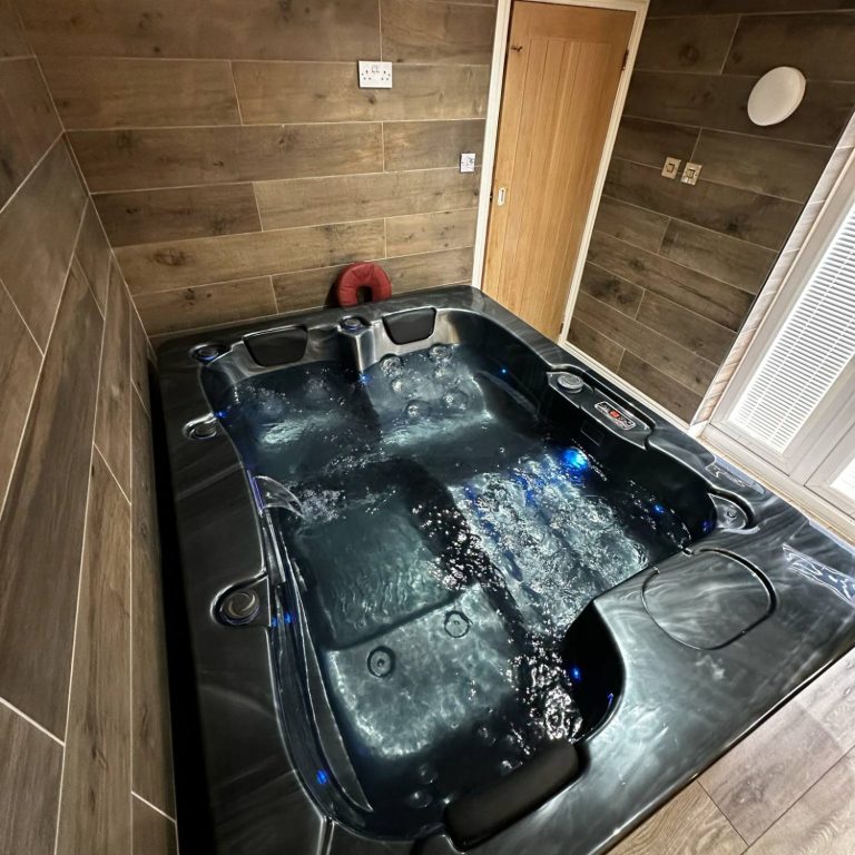 Luxury hot tub with LED lights in a wooden-panelled room.