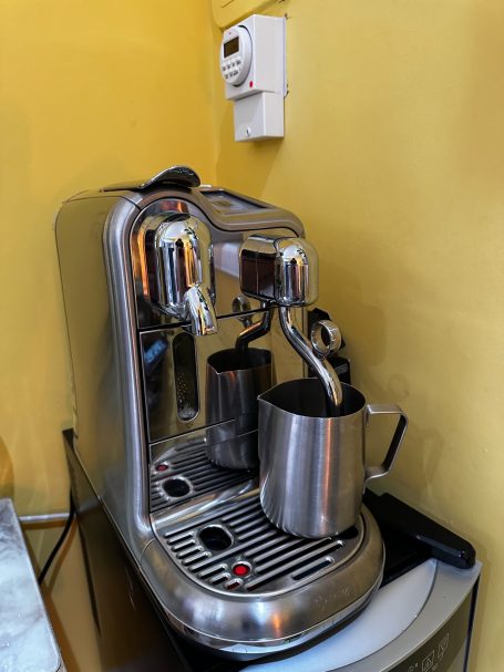 Stainless steel espresso machine with a steam wand and milk frother.