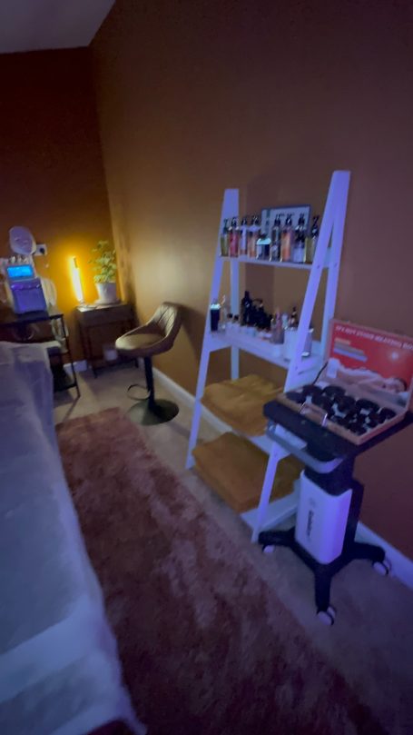 Room featuring a wooden shelf, chairs, and warm lighting against a brown wall.